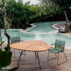 an outdoor table and chairs next to a swimming pool with trees in the back ground