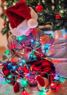 a small child in a santa hat is surrounded by christmas lights