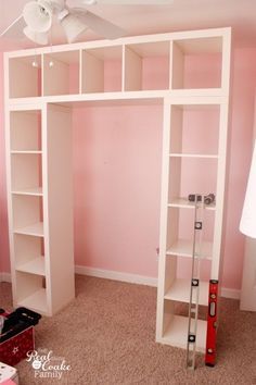 a room with pink walls and white shelving unit in the corner, along with a ceiling fan