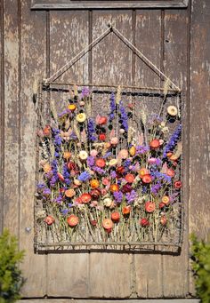 a bunch of flowers are hanging on a wooden door with metal bars attached to it