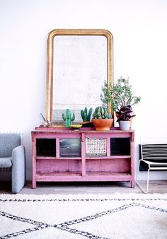 a living room with a mirror, couch and potted plants