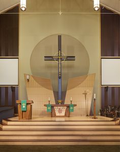 an empty church with wooden steps leading up to the alter and cross on the wall