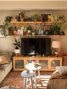 a living room filled with furniture and a flat screen tv mounted on a wooden shelf