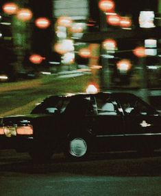 a black car driving down a street at night