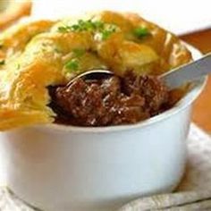 a close up of a bowl of food with meat and cheese in it on a table