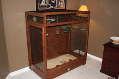 a wooden cabinet with an animal cage in the middle and two pictures above it on top