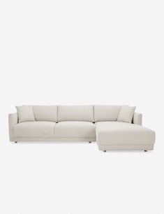 a white sectional couch sitting on top of a white floor next to a wooden table