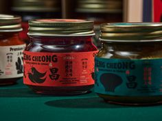 three jars of pickled food sit on a green tableclothed surface with chinese writing