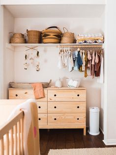 a baby's room with wooden furniture and baskets on the shelves, including a crib