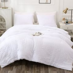 a bed with white comforter and pillows in a room