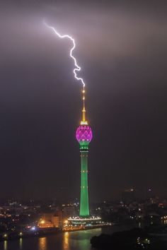 a lightning bolt hitting the top of a tall tower with a green and yellow spire