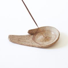 a small bird shaped bowl with an arrow in it's beak and two needles sticking out of the top