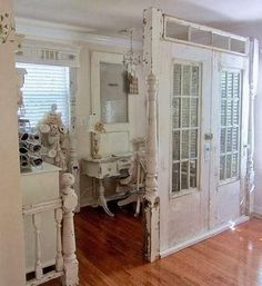 an old white room with wooden floors and french doors that lead into the bathroom area