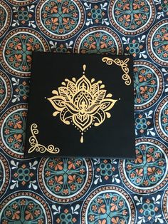 a black and gold book sitting on top of a blue patterned table cloth with an intricate design