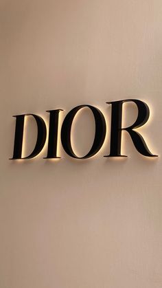 the word dior is illuminated in black on a white wall