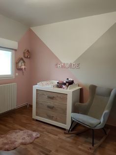 a baby's room with pink walls and white furniture