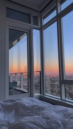 a bedroom with large windows and a view of the city from it's bed