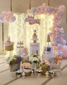 a table topped with lots of balloons and flowers next to a cake on top of a stand