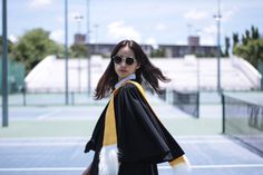 a woman wearing sunglasses and a graduation gown on a tennis court