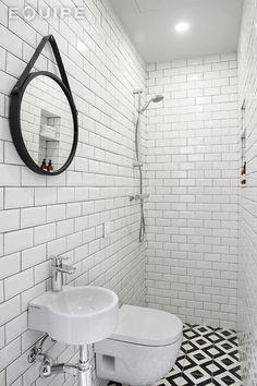 a white toilet sitting next to a sink in a bathroom under a mirror on the wall