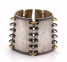 "This is an impressive bracelet by Gurhan a LANCELOT design, it is crafted from solid white and dark silver with yellow gold accent, the bracelet has six hammered design sections four larger and the two end clasp parts smaller, the width of this amazing bracelet is 2.25 inches wide and each section is joined together by 6 rings, the ends are done in a black and silver fancy design, it fastens with a hook in clasp and is hallmark GURHAN. Material: Silver and Yellow Gold Hallmarks: Gurhan Made in Old Fashioned Words, Gold Hallmarks, Hammered Bracelet, Fancy Design, 6 Rings, Wedding Jewelry Bracelets, Gold Accent, Photo Bracelet, Cuff Bangles