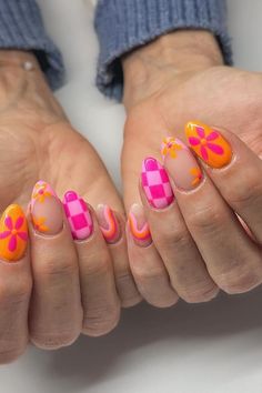 Embrace the vibrancy of summer with these playful almond-shaped nails! A bright orange base sets the stage for whimsical pink flowers, while a creamy, dreamy marble design swirls with hot pink and orange hues. Don't miss the bold statement of the checked pattern, a delightful splash of hot pink that pops with a crisp white cross. This sunny manicure is a celebration of warmth and joy. Simply charming! 🌸🌞  // Photo Credit: Instagram @nailsby.kylierae Pink And Orange Holiday Nails, Bright Almond Nails Designs, Bright Nails With Design, Pink White And Orange Nails, Bright Orange Nails With Design Summer, Summer Pattern Nails, Pink And Orange Checkered Nails, Bold Nails Designs, Hot Pink Holiday Nails