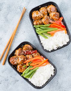 two black trays filled with rice and meat next to chopsticks on a blue surface