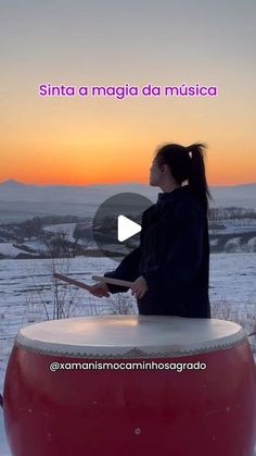 a woman sitting on top of a large red barrel in the middle of a snow covered field