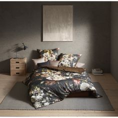 the bed is made up with floral comforter and pillow cases, along with two nightstands