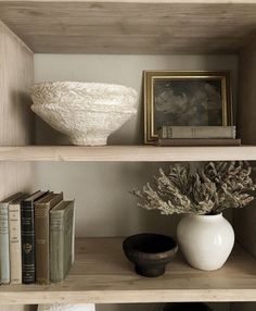 a shelf with books, vase and other items on it