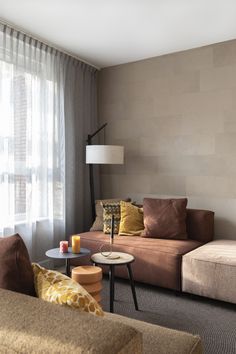 a living room filled with furniture next to a window covered in drapes and curtains