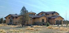 a large house in the middle of a field with trees and bushes on both sides