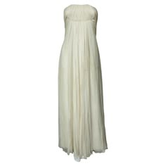 Circa 1970 France Anonymous haute couture evening dress in chiffon and cream silk crepe from the 1970s. Probably from Jean Dessès or Carven designer house(?). An empire-inspired, high-waisted bustier dress with work of pleats at the chest. Beautiful ruffled effect of the skirt with small train and four flounces cut in the bias superimposed on a sheath dress in cream crepe silk. Closure at the back by zip and hook. Haute couture work of the bustier with six integrated underwirings. This dress is White Grad Dress, Empire Waist Dresses, Cream Wedding Dresses, French Couture, Designer House, Couture Evening Dress, Off Shoulder Gown, Slim Aarons, Cream Silk