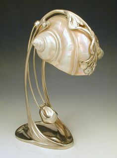 a sculpture of a fish on top of a metal stand with a shell in it's mouth