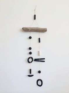 a clock made out of black and white objects hanging on a string with a piece of wood sticking out of it