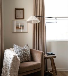 a living room with a chair, lamp and pictures hanging on the wall above it