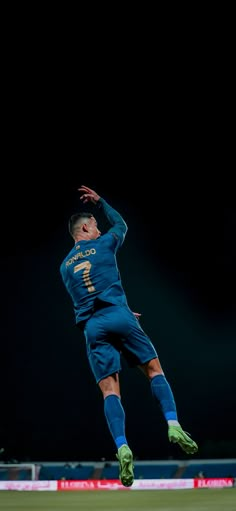 a soccer player jumping up in the air to catch a ball with his head and legs