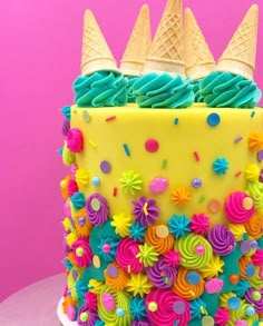 a brightly colored cake with ice cream cones on top and sprinkles all over it