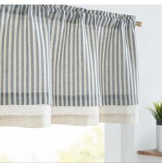 a striped curtain hanging on the side of a window next to a potted plant