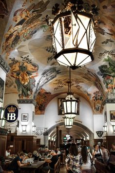 people sitting at tables in a restaurant with paintings on the ceiling