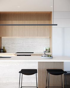 two stools are sitting at the bar in this modern kitchen with white countertops and wood paneling