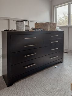 an empty room with a dresser and large window