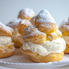 several pastries on a plate with powdered sugar and icing are arranged in the shape of cones