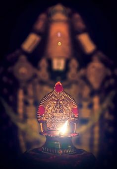 a lit candle with an intricate design on it in front of a dark background that appears to be blurry