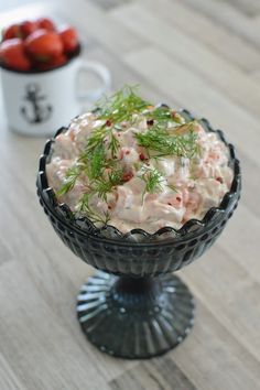 a bowl filled with food sitting on top of a wooden table next to a cup