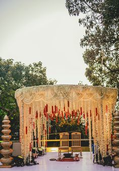 an outdoor wedding setup with white flowers and red candles on the altar, surrounded by trees