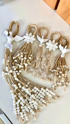 some white flowers and pearls are arranged on a counter top next to other items that have been made out of twine string