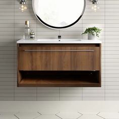 a bathroom vanity with a round mirror above it and white tiles on the wall behind it