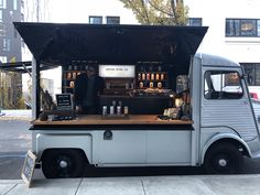 an old truck is parked on the side of the road with its door open and people standing at the bar