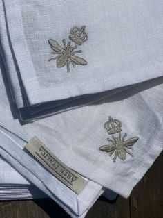 three folded napkins with embroidered bees on them sitting next to each other in front of a wooden table